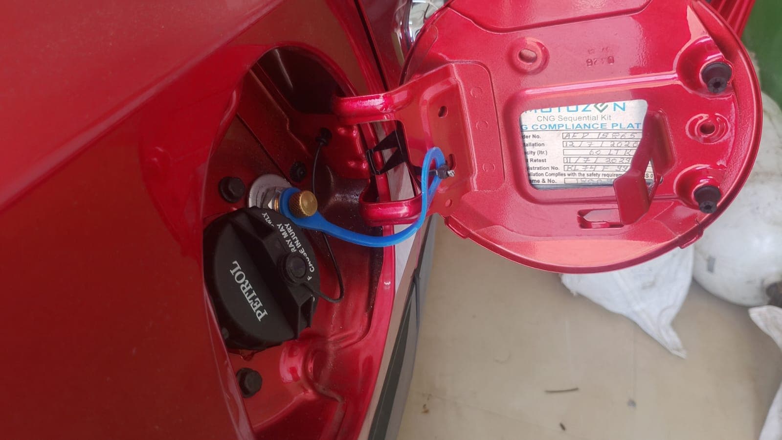 CNG filling receptacle beside the petrol cap, with the compliance plate on the fuel flap